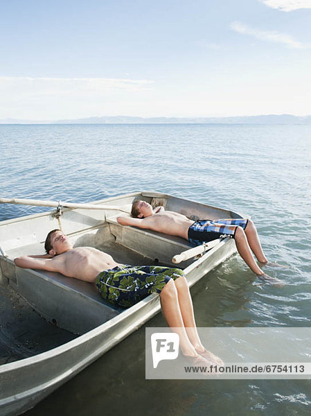 Boys (10-11 12-13) resting on boat