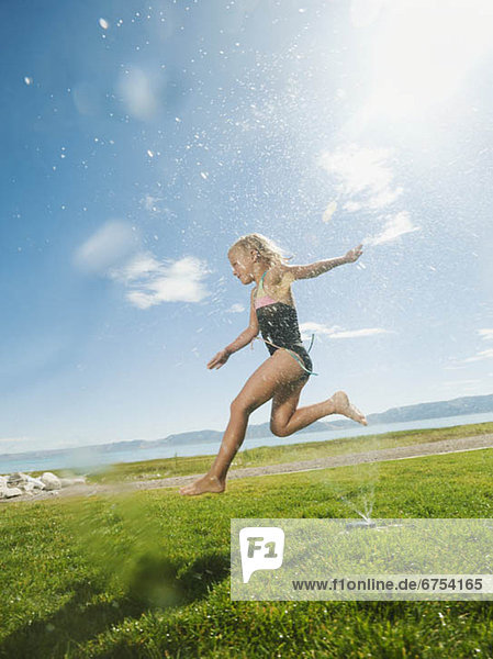 Girl (8-9) jumping over watering system
