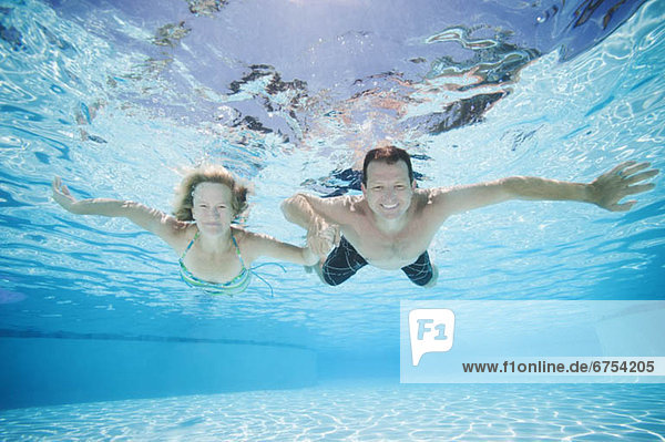 Mid adult couple swimming underwater