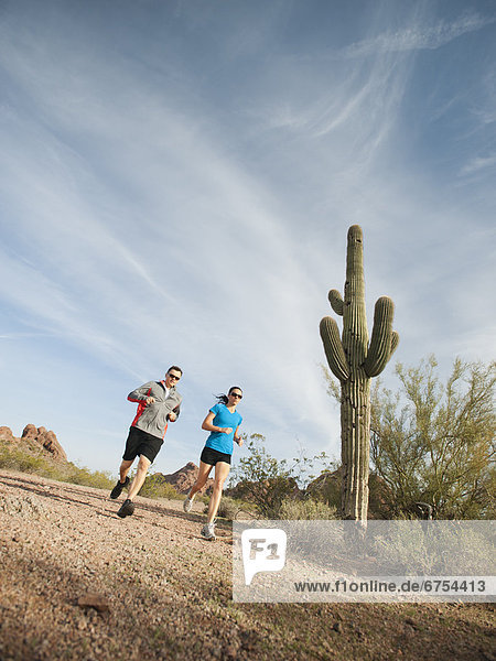 USA  Arizona  Phoenix  Mid adult man and young woman jogging on desert