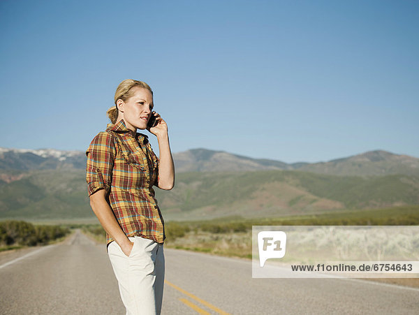 USA  Utah  Kanosh  Mid adult woman calling emergency services on empty desert road