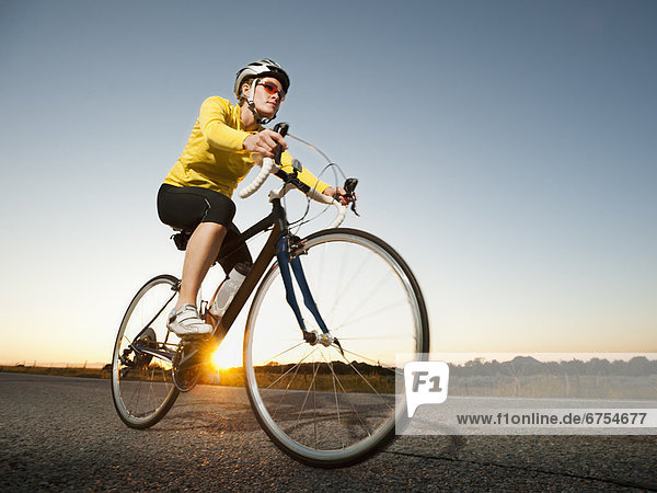 Mid adult woman cycling on empty road