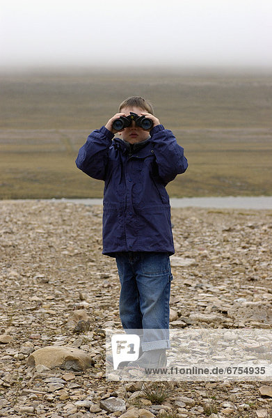 Boy using binoculars  Nunavut  Base of Mount Pelly  Victoria Island.