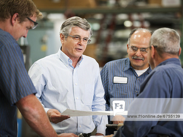 Businessman and workers talking in factory