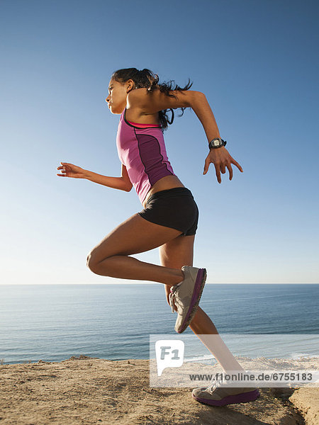 USA  California  San Diego  Woman jogging along sea coast