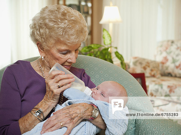 Senior woman giving milk to grandson (2-5 months)