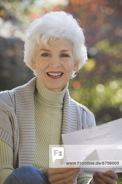 Portrait of senior woman holding mail outdoors