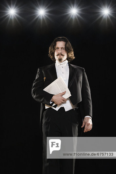 Man in tuxedo holding sheet music