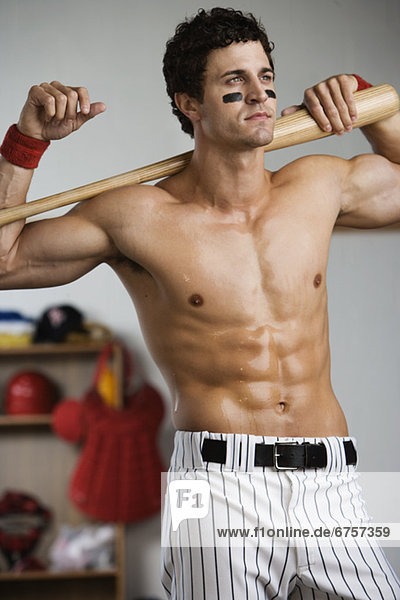 Baseball player with bare chest posing in locker room