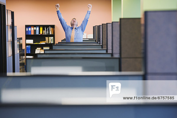 Businessman cheering in cubicle