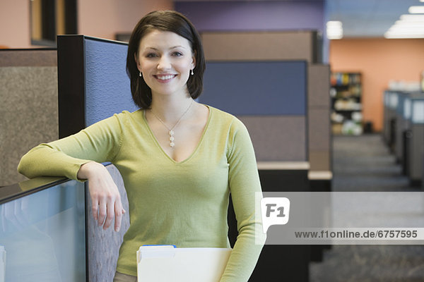 Businesswoman leaning on cubicle wall