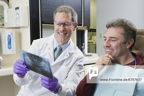 Male dentist and patient looking at x-ray