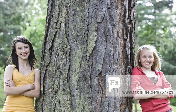 Girls leaning against large tree
