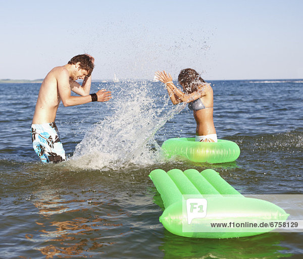 Young couple splashing in ocean