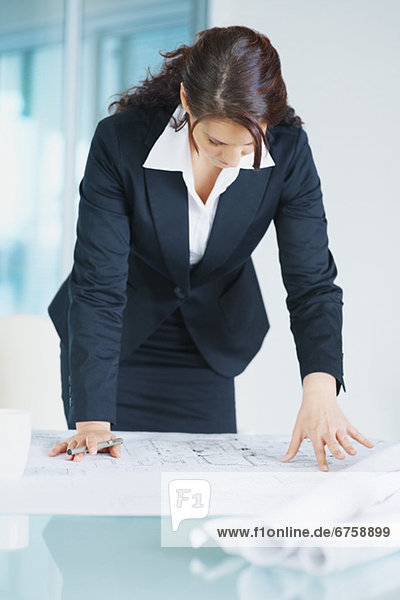 Businesswoman looking at blueprints
