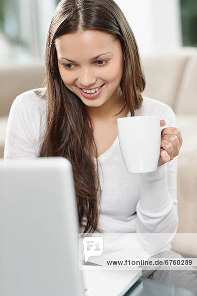 Woman drinking coffee while browsing the internet