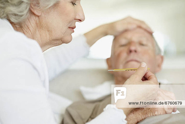 Senior woman caring for man with a fever