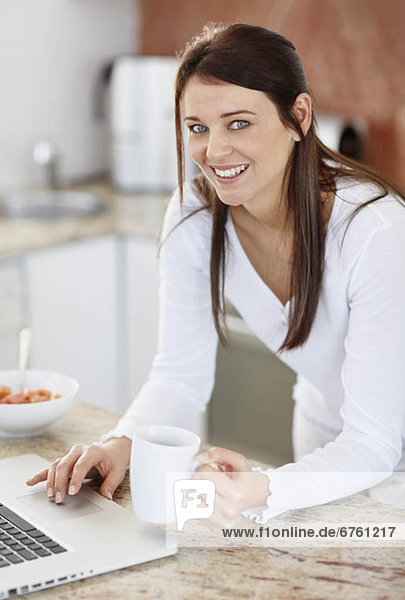 Mid adult woman using laptop in kitchen