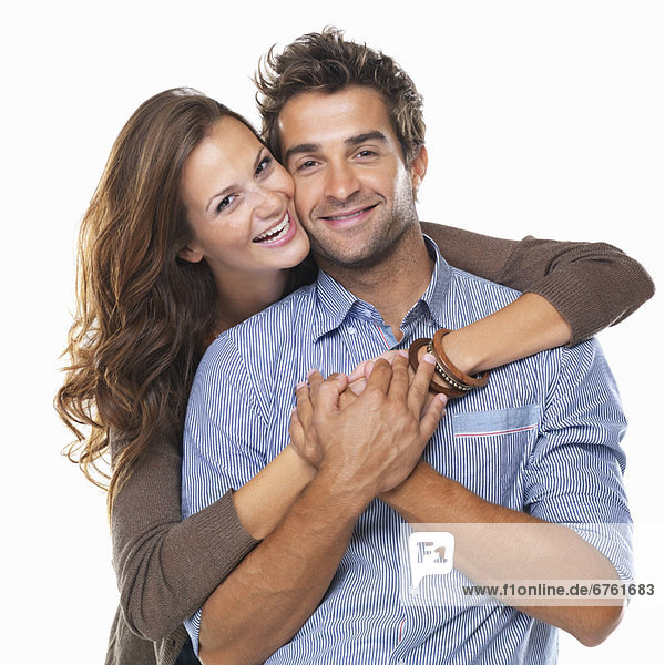 Studio shot of young couple smiling and embracing