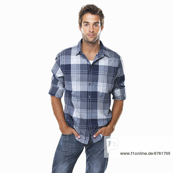 Studio shot of young confident man with hands in pockets