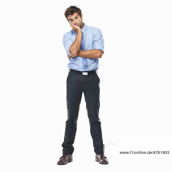 Full length of bored business man standing with hand on face against white background