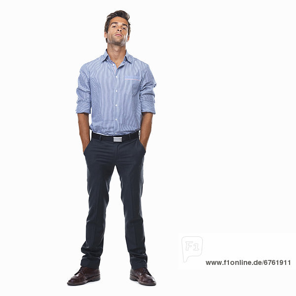 Studio shot of young business man standing with hands in pockets