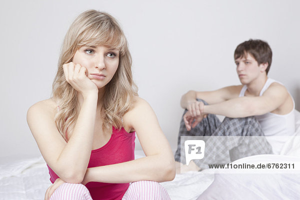 Couple sitting on bed after arguing