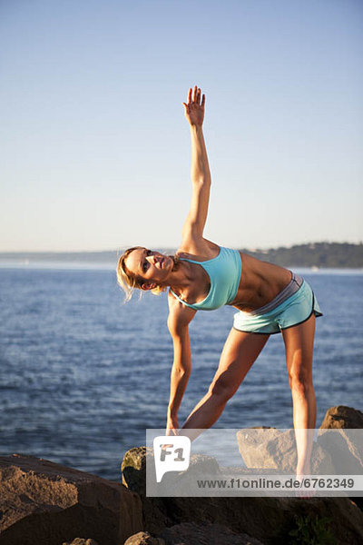 Athletic woman stretching by the ocean