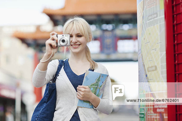USA  Seattle  Young woman taking photos and holding map