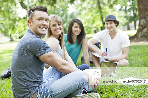 Portrait of college students relaxing on grass