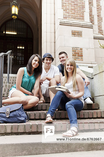 Portrait of four college students sitting on steps
