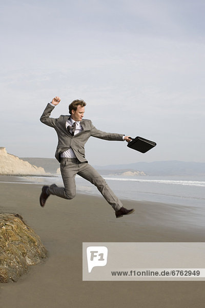 Businessman jumping on beach