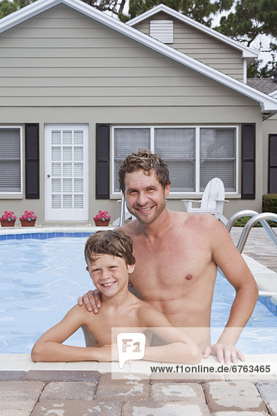 Father and son posing in swimming pool