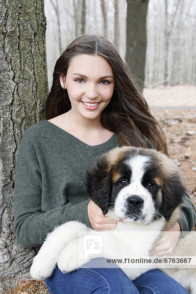 USA  New Jersey  Califon  Teenage girl (16-17) sitting with Saint Bernard puppy on laps  portrait