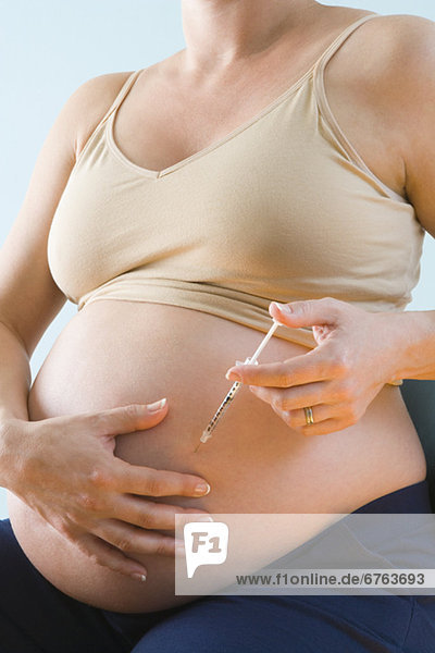 Pregnant woman injecting belly