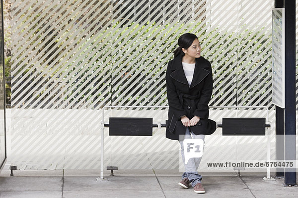Young woman waiting at bus stop  San Francisco  California  USA