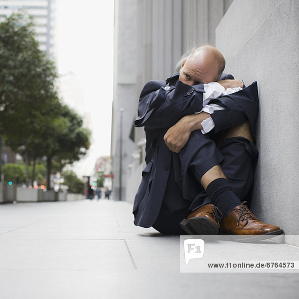 Businessman wearing torn clothing  sitting on sidewalk  San Francisco  California  USA