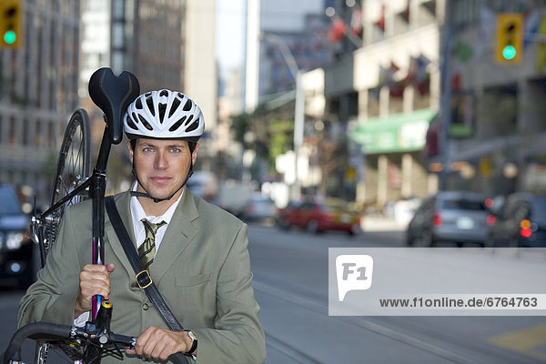Businessman holding his bicycle on street  Toronto  Ontario