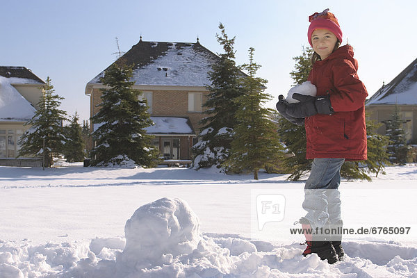 Girl Making Snowman in Suburban Neighbourhood