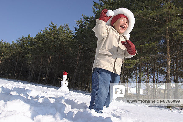 Boy throwing Snowball with Snowman in Background