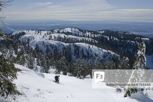 Man skiing below Mount Seymour with city in distance  Mount Seymour Provincial Park  Vancouver  British Columbia