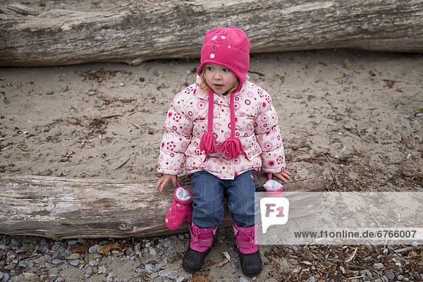 Small girl sitting on log  Lake Ontario  Ontario