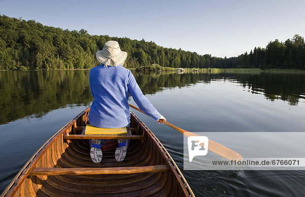 Woman paddling canoe on Smoke Lake  Algonquin Park  Ontario