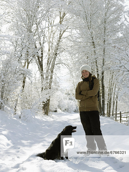 USA  Colorado  young woman playing with dog on snowy road