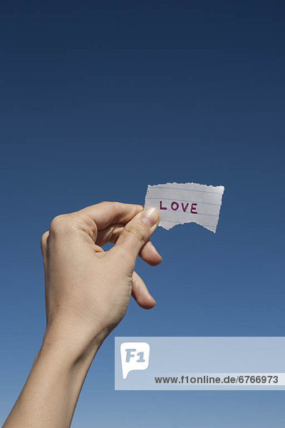 USA  Arizona  Winslow  Human hand holding love note against blue sky