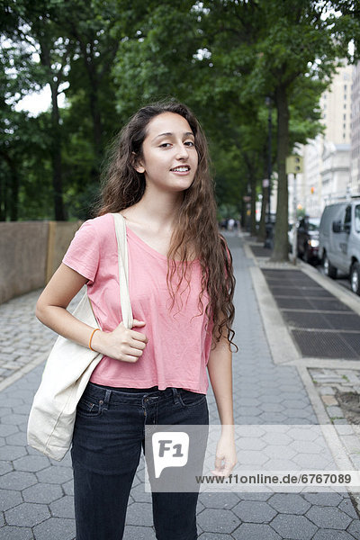 USA  New York  New York City  Portrait of smiling young woman standing on street