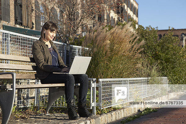 USA  New York City  Brooklyn  woman on bench using laptop