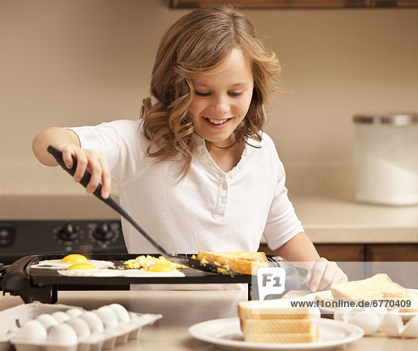 Girl (10-11) preparing breakfast in kitchen