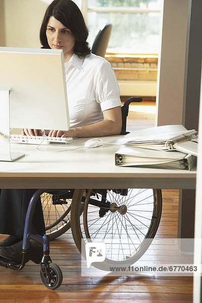 Behindertensport Frau arbeiten Büro Behinderung Rollstuhl