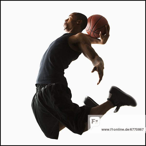Studio shot of young man playing basketball